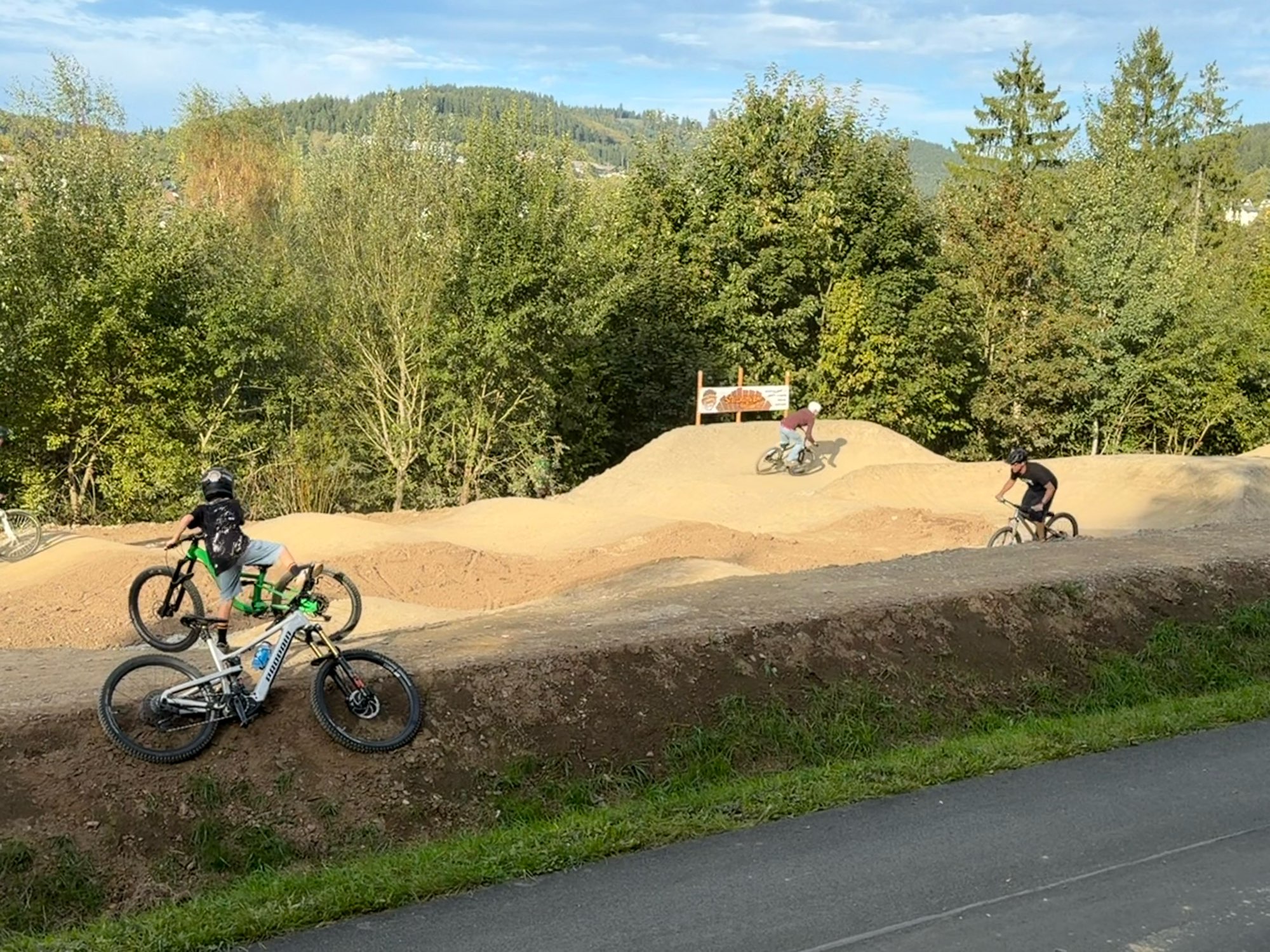 Biker auf den Wellen des Pumptracks, Bikes am Streckenrand – Pumptrack Bikeparcours Bad Fredeburg