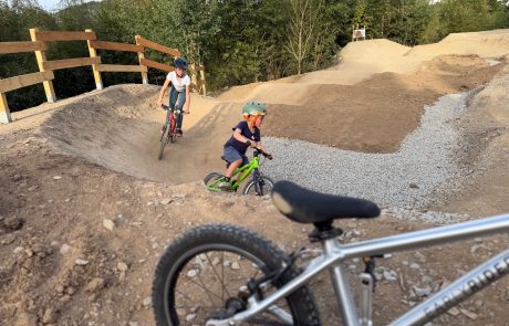 Kinder fahren durch die Steilkurve am Holzgeländer – Pumptrack Bikeparcours Bad Fredeburg